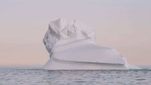 A large iceberg floats calmly in the Arctic sea during a soft pink sunset, 4K Desktop Wallpaper