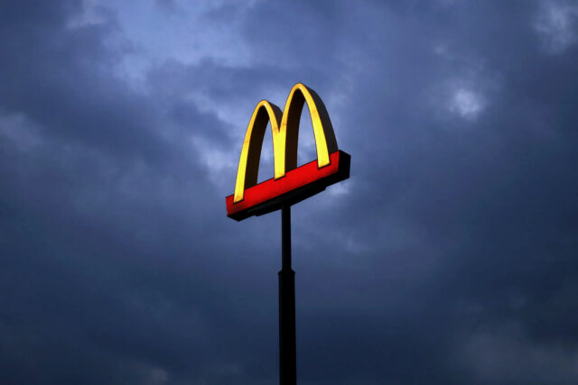 McDonalds Sign Illuminated Against Dark Cloudy Evening Sky Wallpaper