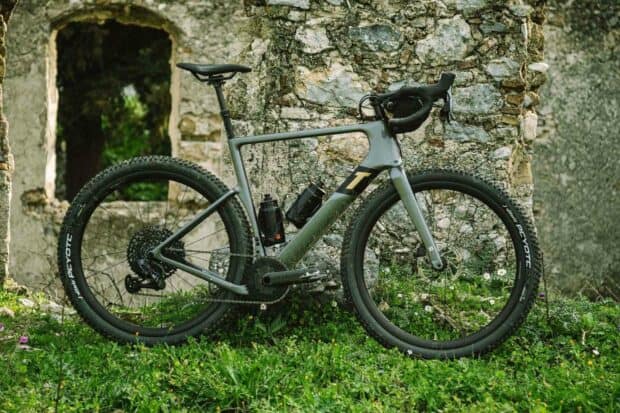 A 3T bike with two water bottles stands on grass near an old stone wall, HD Desktop Wallpaper