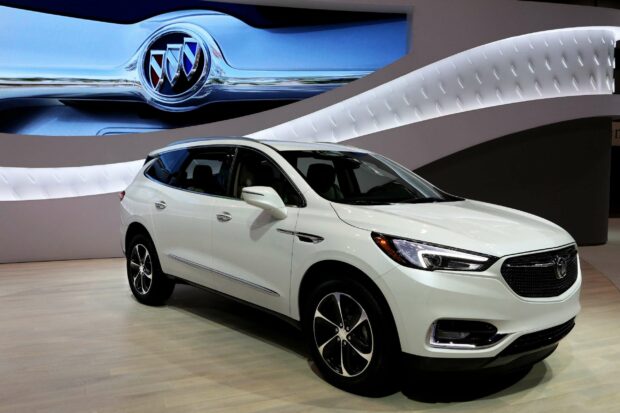 A white Buick Enclave is displayed indoors with illuminated headlights and a detailed grille, 2K Desktop Wallpaper