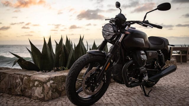 Moto Guzzi V7 Classic Motorcycle Parked by Ocean at Sunset Wallpaper
