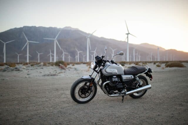 Moto Guzzi V7 Classic Motorcycle in Desert with Wind Turbines Background