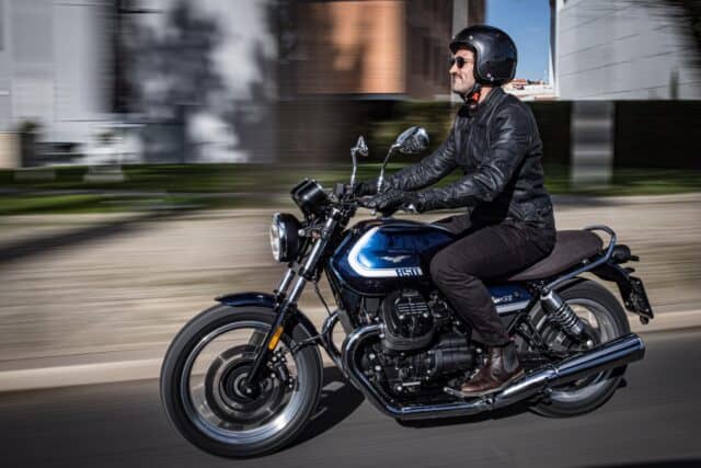 Moto Guzzi V7 Rider Cruising on Classic Blue Motorcycle Wallpaper