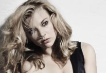 Natalie Dormer Elegant Portrait Pose, A Portrait Of Natalie Dormer Sitting Against A White Wall Wearing A Black Dress With Tousled Hair, 4K Phone Wallpaper