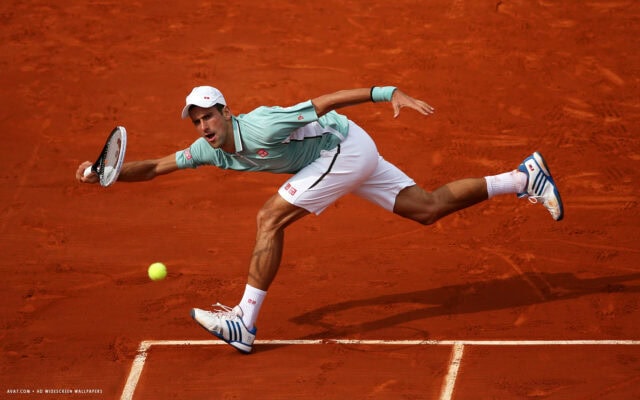 Novak Djokovic In Action On Clay Court For Wallpaper