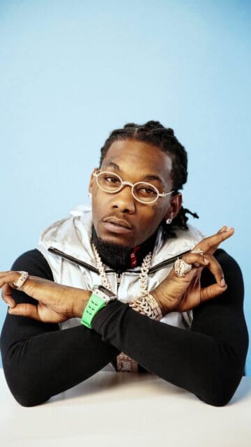 Offset rapper stylish portrait with luxury jewelry and green watch on blue background wallpaper