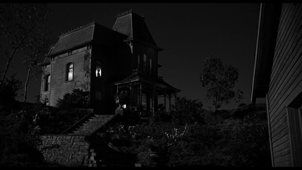 The dark gothic house featured in Alfred Hitchcock Wallpapers is shown at night with dimly lit windows, HD Desktop Wallpaper