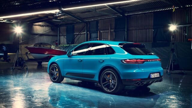 Porsche Macan in vibrant blue parked inside modern garage with spotlight reflections