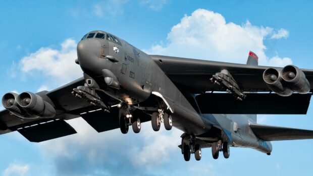 A Boeing B 52 is captured flying with its landing gear down against a blue sky, 2K Desktop Wallpaper