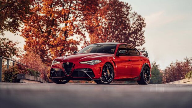 A red Alfa Romeo car is parked on the road surrounded by autumn trees with orange leaves, 4K Desktop Wallpaper