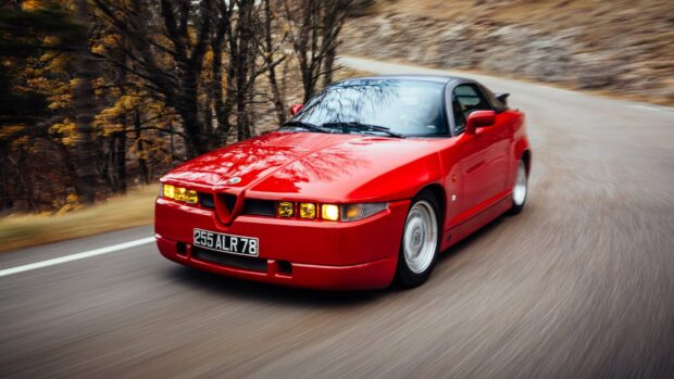 A red Alfa Romeo is driving fast through a winding forest road, 2K Desktop Wallpaper