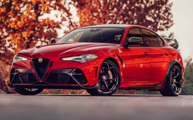 A red Alfa Romeo car is parked on a reflective surface with orange autumn trees in the background, HD Desktop Wallpaper