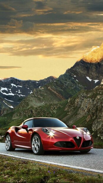 A red Alfa Romeo is parked on a mountain road with rocky hills and a cloudy sky in the background, HD Phone Wallpaper