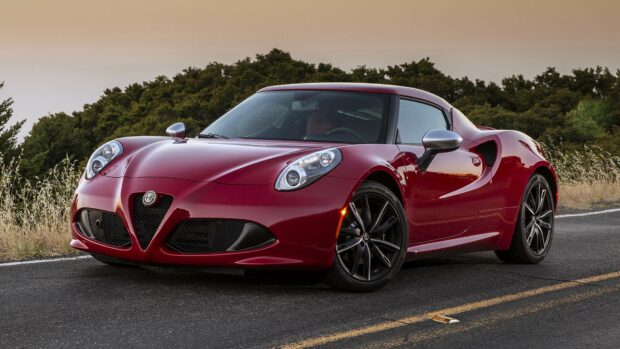 A red Alfa Romeo is parked on an empty road with trees in the background during sunset, 4K Desktop Wallpaper