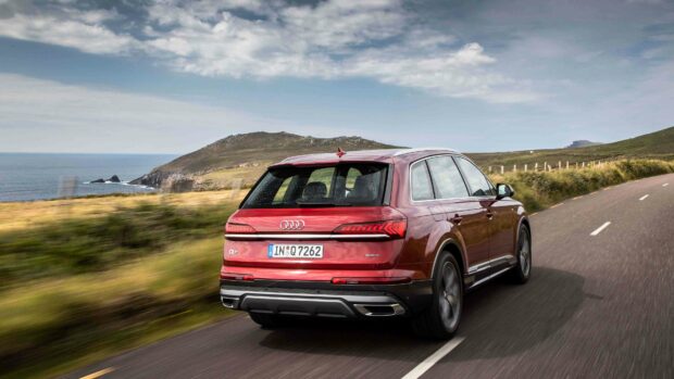 A red Audi Q7 is driving on a winding road near the coast with hills and ocean in the background, 4K Desktop Wallpaper