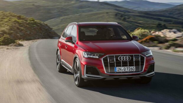 A red Audi Q7 is driving along a winding mountain road surrounded by rocky hills, 4K Desktop Wallpaper