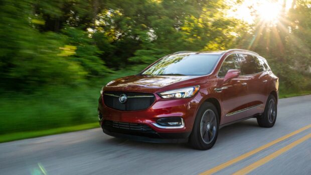 A red Buick Enclave is driving on a forest road with sunlight shining through the trees, 4K Desktop Wallpaper
