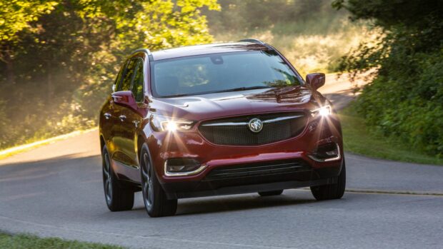 A red Buick Enclave drives along a tree lined road with its headlights on, 4K Desktop Wallpaper