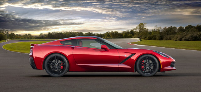 Red Chevrolet Corvette Sports Car On Race Track Background Wallpaper