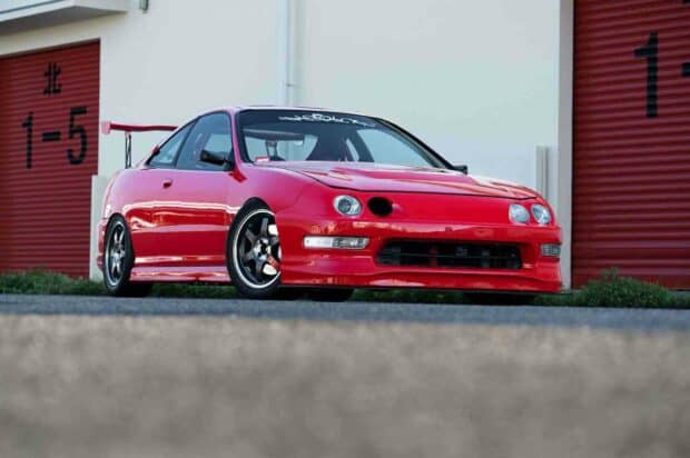 A red Honda Integra parked in front of garage doors with a clear daytime sky, HD Desktop Wallpaper