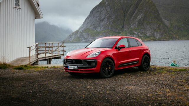 Red Porsche Macan parked by lakeside with mountain background in high resolution wallpaper