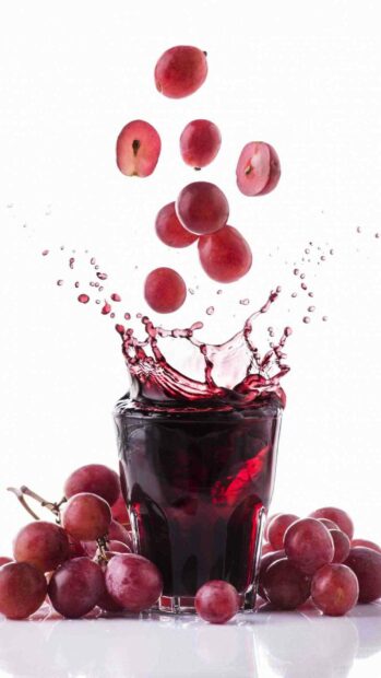 Red grapes splash into the glass of juice surrounded by fresh grape clusters, HD Phone Wallpaper
