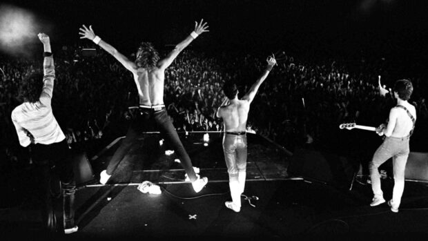 A rock band performs energetically on stage in front of a large audience during a concert, HD Desktop Wallpaper