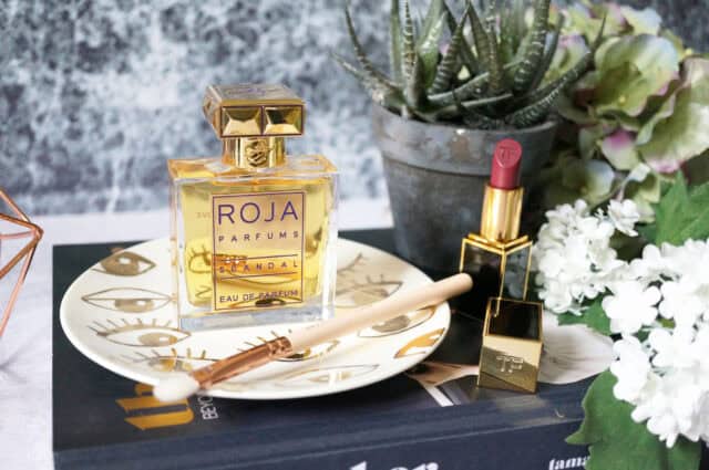 Roja Dove Scandal Perfume And Lipstick Display With Floral Decor