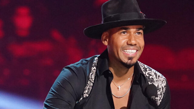 Romeo Santos Smiling on Stage Vibrant Wallpaper Background