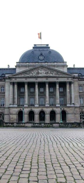 A royal historic building in Brussels with a Belgian flag flying on top and cobblestone pavement in front, HD Phone Wallpaper