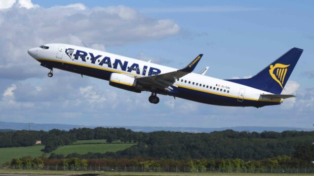 A Ryanair airplane is shown taking off over a green landscape under a partly cloudy blue sky, 4K Desktop Wallpaper