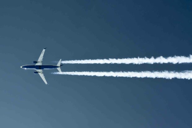 A Ryanair airplane leaves trails as it flies in a clear blue sky, 2K Desktop Wallpaper