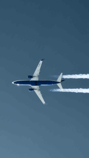 A Ryanair airplane soars high with clear contrails behind it in the bright blue sky, HD Phone Wallpaper