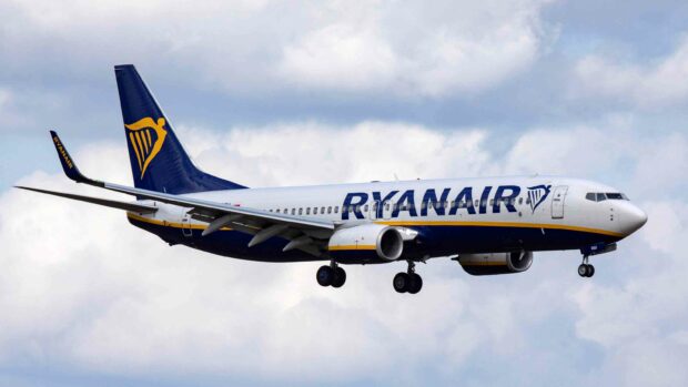 A Ryanair airplane is captured flying with landing gears down against a cloudy sky, 2K Desktop Wallpaper