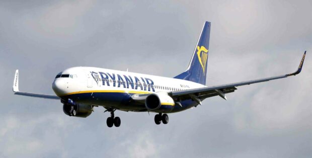 A Ryanair airplane is captured flying against a cloudy sky, 2K Desktop Wallpaper