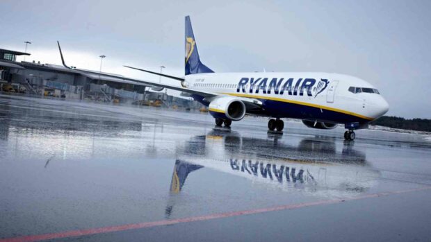 A Ryanair airplane is parked on a wet runway with its reflection visible on the surface, HD PC Wallpaper