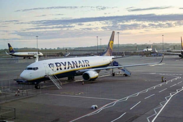 A Ryanair plane is parked at the airport with other planes in the background during sunrise, HD Desktop Wallpaper