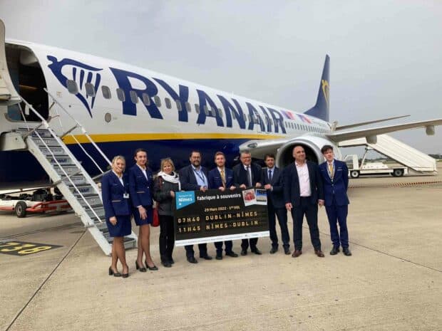 A group of Ryanair staff and officials pose in front of a Ryanair airplane on the tarmac holding a sign with flight details, HD Desktop Wallpaper
