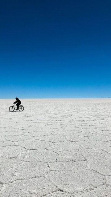 Salar De Uyuni Bolivia Vast Salt Flat with Cyclist Under Clear Blue Sky Wallpaper