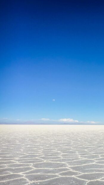 The vast salt flats extend under a clear blue sky with distant mountains on the horizon, HD Mobile Wallpaper