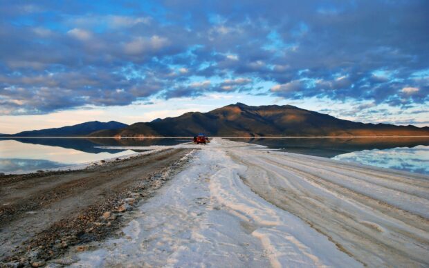 The Bolivia Wallpapers image shows a salt flats road leading towards mountains under a dramatic sky, 2K Desktop Wallpaper