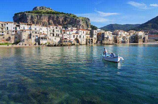 Scenic Cefalù Seaside Town With Boat And Cliff Wallpaper