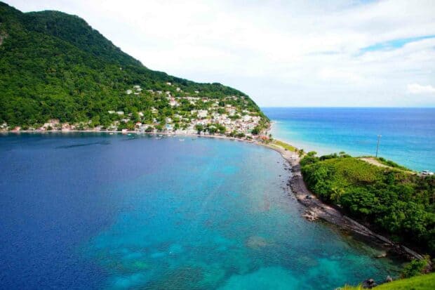 A coastal village on Dominica island is surrounded by lush hills and clear blue waters, showcasing the natural beauty of Dominica wallpapers, HD Desktop Wallpaper