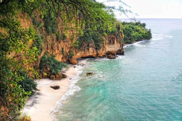 A secluded beach with cliffs and turquoise water in Dominica showcasing natural beauty, 2K Desktop Wallpaper
