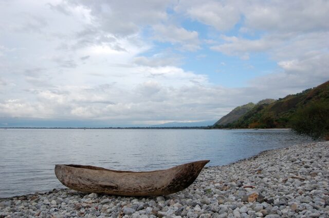 Serene Lake Malawi View With Canoe On Rocky Shoreline