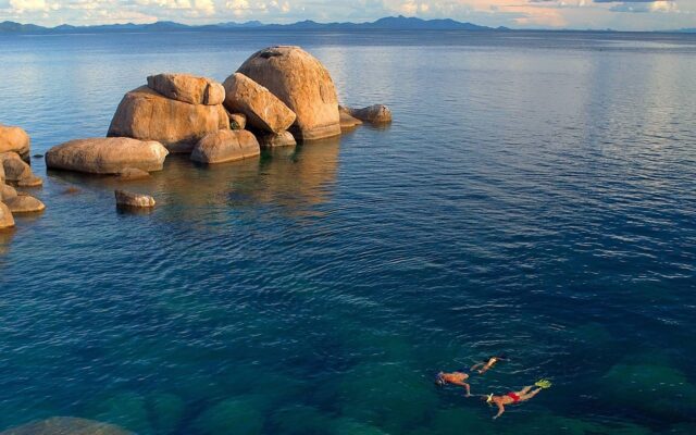 Serene Lake Malawi Waterscape With Snorkelers And Rocks