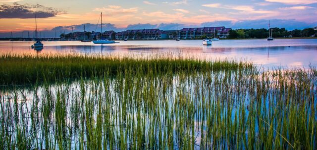 Serene South Carolina Waterfront with Sailboats and Coastal Marsh Grass Sunset Wallpaper