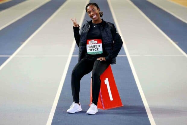 Shelly Ann Fraser Pryce is sitting on a numbered marker on a track while smiling and making a peace sign, HD Desktop Wallpaper