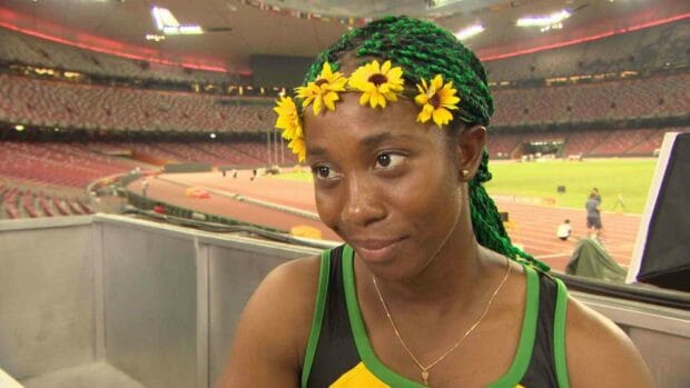 Shelly Ann Fraser Pryce wears a yellow flower crown and green sports attire at the stadium, HD Desktop Wallpaper