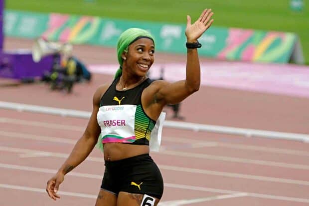 Shelly Ann Fraser Pryce smiles and waves while standing on the running track at a competition, HD Desktop Wallpaper
